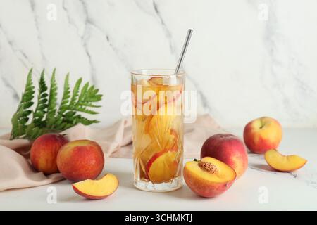 Serviette und Glas leckeren Pfirsicheistees auf Marmorhintergrund, Nahaufnahme Stockfoto