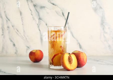 Glas leckerer Pfirsicheistee auf Marmorhintergrund, Nahaufnahme Stockfoto