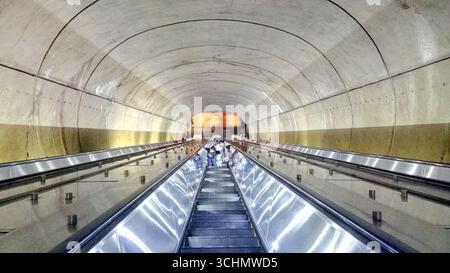 Pendler auf der langen Rolltreppe an der Metrostation Dupont Circle in Washington, D.C., umgeben von bogenförmigen Tunnelarchitekturen. Stockfoto