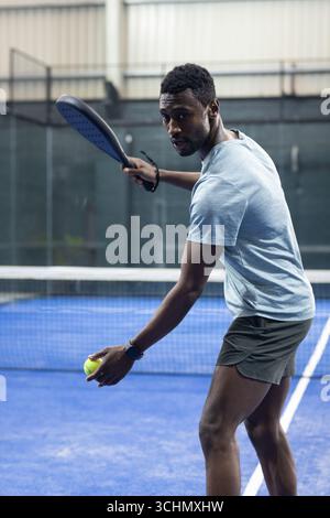 afroamerikaner, der auf dem Hof mit schwarzem Paddel mit Tennisball dient, Kopierraum Stockfoto