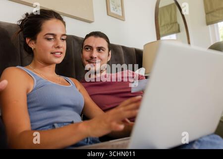 Kombinieren Sie Online-Shopping mit Laptop, lächeln Sie und genießen Sie die gemeinsame Zeit zu Hause Stockfoto