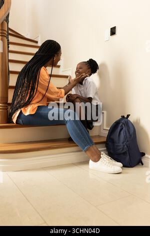 Mutter und Tochter sitzen auf der Treppe und teilen einen freudigen Moment vor der Schule Stockfoto