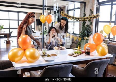 Überraschender Kollege mit Geburtstagsfeier, Kollegen im Büro mit Ballons Stockfoto