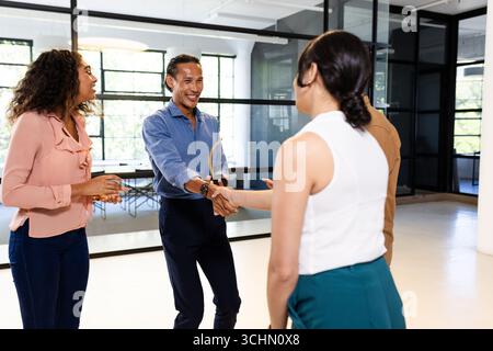 Im modernen Büro grüßen sich verschiedene Geschäftsteams gegenseitig mit Handschütteln Stockfoto
