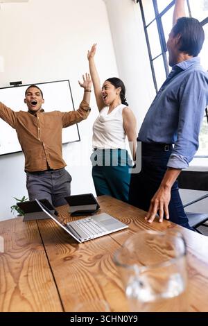 Geschäftsteam feiert Erfolg mit erhobenen Armen im modernen Büro Stockfoto