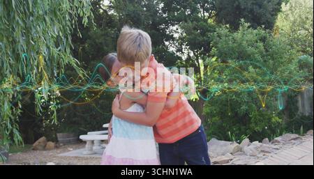 Umarmte Geschwister in Pastellkleid und gestreiftem T-Shirt im Garten mit Wellenform-Überzug Stockfoto