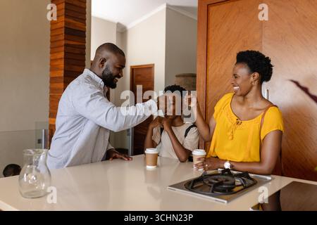 Familie genießt morgens Kaffee in der Küche und teilt fröhliche Faustschläge Stockfoto