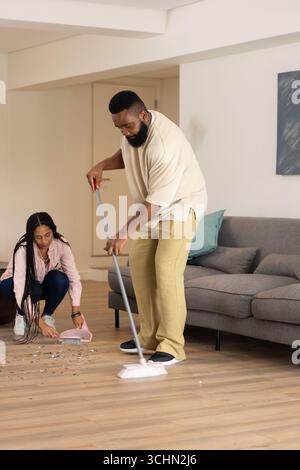 Der Vater kehrt den Boden, während die Tochter zu Hause Trümmer sammelt und die Familienzeit genießt Stockfoto