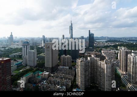 Aus der Vogelperspektive auf eine dichte Skyline der Stadt mit einem markanten Wolkenkratzer, einem fernen See und Bergen unter einem bewölkten Himmel. Stockfoto