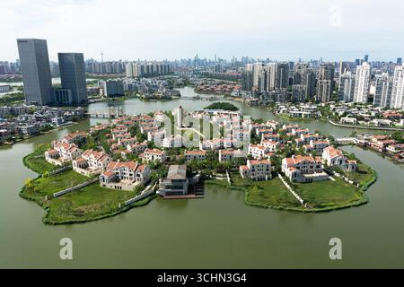 Blick aus der Vogelperspektive auf eine exklusive Inselgemeinschaft mit luxuriösen Villen im Kontrast zur modernen Skyline der Stadt Suzhou in China. Stockfoto