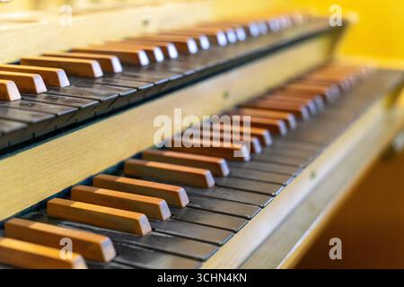 Antike Orgeltastatur und Bedienelemente in einer lutherischen Kirche. Notenblätter mit Notizen liegen auf dem Ständer. Stockfoto