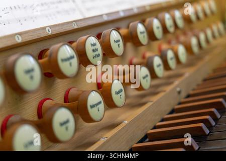 Antike Orgeltastatur und Bedienelemente in einer lutherischen Kirche. Notenblätter mit Notizen liegen auf dem Ständer. Stockfoto