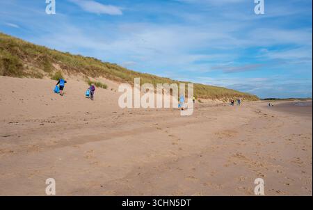 Eine Gruppe von Mühlenpflückern, die freiwillig den Strand entlang der Küste in Druridge Bay, Northumberland, aufräumen. Stockfoto