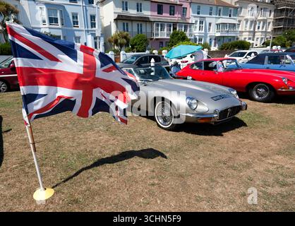 Eine große Union Jack Flagge fliegt neben einem 1972, Silber, Jaguar E-Type, Serie 3, Roadster, während des Deals und der Walmer Classic Car Show 2025 Stockfoto