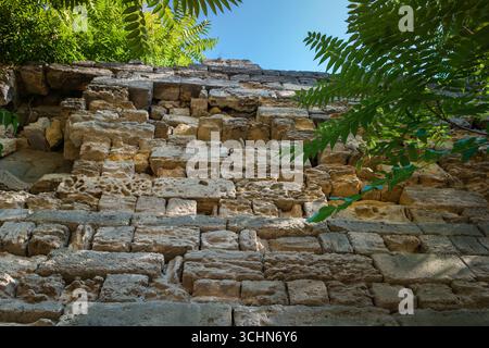 Alte, gelbe Kalksteinfestungsmauer, die sich langsam verschlechtert und aufgrund der Umweltbelastung zerbricht Stockfoto