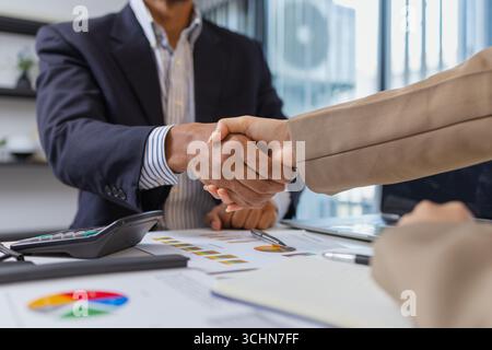 Geschäftspartner schließen ihre Besprechung mit einem Handschlag ab, der Vertrauen, Zustimmung und erfolgreiche Zusammenarbeit symbolisiert. Sie bestätigen Entscheidungen nach einem Stockfoto