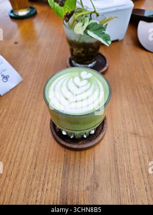 Grüner Matcha Latte im Glas auf Holztisch, cremiges Getränk mit natürlichem Geschmack Stockfoto