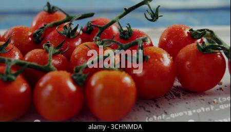 Zeigt Tomatenstrauch auf der Weinrebe, glitzernd mit Wassertröpfchen auf der Tischplatte mit gedrucktem Text Stockfoto