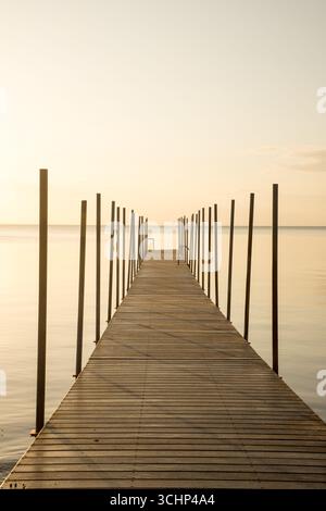 Goldener Sonnenaufgang über hölzerne Badebrücke an der dänischen Nordküste am frühen Morgen, goldener Ozean Natur Hintergrund Stockfoto