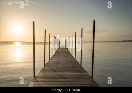 Goldener Sonnenaufgang über hölzerne Badebrücke an der dänischen Nordküste am frühen Morgen, goldener Ozean Natur Hintergrund Stockfoto