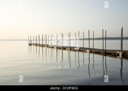 Goldener Sonnenaufgang über hölzerne Badebrücke an der dänischen Nordküste am frühen Morgen, goldener Ozean Natur Hintergrund Stockfoto