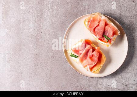 Toast mit Frischkäse und Marmelade. Prosciutto Crudo offenes Sandwich oder Bruschetta mit Rosmarin, Brot und Öl. Stockfoto