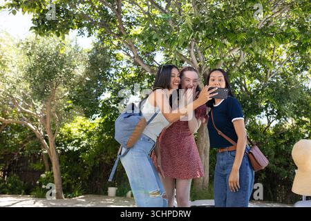 Drei junge Frauen lachen und posieren für Selfie. Sie genießen einen sonnigen Tag im Freien Stockfoto