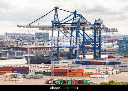 Containerschiff im Kopenhagener Hafen Malmö Dänemark // KOPENHAGEN, Dänemark — Ein großes Containerschiff ist im Kopenhagener Hafen Malmö angedockt, einem wichtigen Seeknotenpunkt, der sowohl Dänemark als auch Schweden bedient. Der Hafen verfügt über zahlreiche Portalkräne, die für das Be- und Entladen von Frachtcontainern von Schiffen unerlässlich sind. Zahlreiche Transportcontainer, darunter die aus Maersk, Hapag-Lloyd und Unifeeder, sind auf dem Kai gestapelt. Die Infrastruktur des Hafens unterstützt bedeutende internationale Handels- und Logistikoperationen. Der Hafen von Kopenhagen Malmö liegt strategisch günstig in der Straße von Øresund, was eine effiziente Verkehrsführung ermöglicht Stockfoto