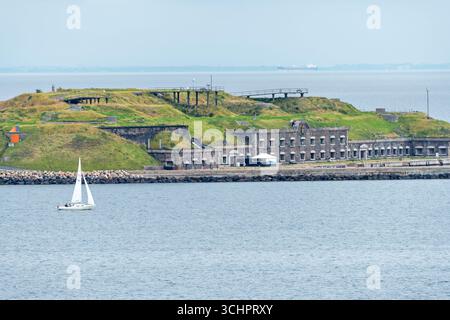 Flakfortet Charlottenlund Dänemark // CHARLOTTENLUND, Dänemark — Flakfortet, eine ehemalige Militärbefestigung, ist vom Wasser aus mit einem Segelboot in der Nähe zu sehen. Das Fort befindet sich in der Meerenge von Øresund nördlich von Kopenhagen und wurde zwischen 1910 und 1914 als Teil des dänischen Küstenverteidigungssystems errichtet. Es liegt auf einer künstlichen Insel und verfügt über eine markante Festung, die in die Landschaft eingebettet ist. Die Festung spielte eine Rolle in der dänischen Verteidigungsstrategie während der beiden Weltkriege. Heute ist Flakfortet eine historische Stätte und ein beliebtes Ziel für Freizeitaktivitäten. Das Kapital R Stockfoto