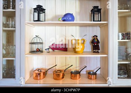 Kupfersoßen in der Provence Home Saint Martin de Crau Frankreich // SAINT-MARTIN-DE-CRAU, Frankreich — traditionelle Kupferkochtöpfe und Kochtöpfe werden in einem provenzalischen Haus ausgestellt und zeigen das kulinarische Erbe der Region. Diese gut gepflegten Kupfergefäße spiegeln einen traditionellen französischen Ansatz bei Koch- und Küchengeräten wider. In den Regalen befinden sich auch dekorative Gegenstände wie Laternen, Keramikfiguren und Glaswaren, die zum rustikalen Charme des Innenraums beitragen. Die Ausstellung befindet sich in der Region Provence les Alpilles, die für ihre reichen kulturellen Traditionen und Gastrono bekannt ist Stockfoto