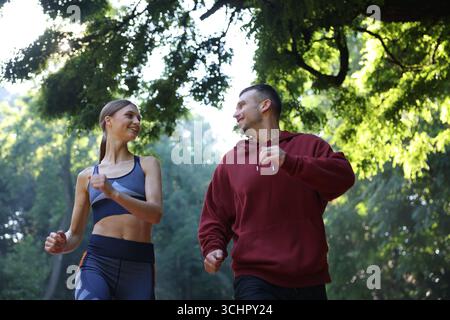 Junge Frau, die mit professionellem Personal Trainer im Freien läuft, geringer Blickwinkel Stockfoto