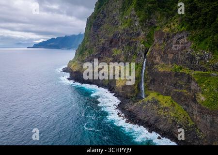 Blick aus der Vogelperspektive auf einen Wasserfall, der im Frühjahr direkt im Meer an der Küste von Seixal liegt. Madeira, Portugal, Europa. Stockfoto