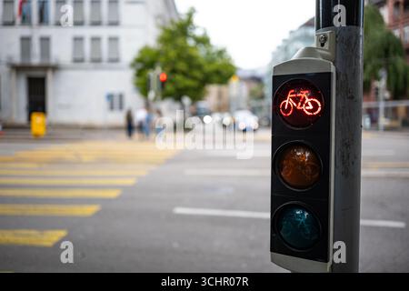 Fahrradampel neben Fußgängerübergang, rot. Nahaufnahme, Weitwinkelaufnahme, geringe Schärfentiefe, unscharfer Hintergrund und Personen Stockfoto
