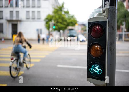 Fahrradampel neben Fußgängerübergang, grün. Nahaufnahme, Weitwinkelaufnahme, geringe Schärfentiefe, unscharfer Radfahrer im Hintergrund Stockfoto