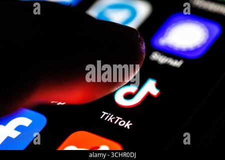 Norden, Deutschland. September 2025. Das Logo der TikTok App ist am 2. September 2025 durch eine Lupe auf dem Display eines Smartphones zu sehen, während sich ein Zeigefinger dem Symbol der Anwendung nähert. TikTok ist ein Videoportal für kurze Videos, das auch soziale Netzwerkfunktionen bietet und von der chinesischen Firma ByteDance betrieben wird. (Symbolbild, Symbolfoto, Illustration, symbolisches Foto, illustratives Foto, Themenbild, allgemeines Bild, Themenfoto) Credit: Matthias Balk/dpa/Alamy Live News Stockfoto