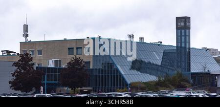 LUXEMBURG, EUROPA - 1. SEPTEMBER 2025 - Luxexpo The Box Gebäude mit Glasfassade, die den bewölkten Himmel reflektiert, und geparkten Autos in der Stadt Luxemburg Stockfoto