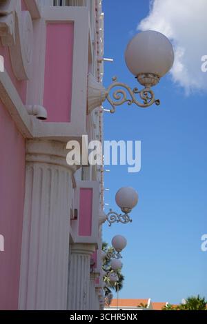 Aruba, Oranjestad - Eindruck von der Straße mit abstrakter Vintage-Fassade in Rosa mit weißen Laternen bei Sonnenuntergang Stockfoto