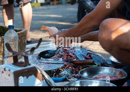 Fischhändler säubern Fische zum Verkauf in einem traditionellen Stand für frischen Fisch und Meeresfrüchte in Indonesien Stockfoto