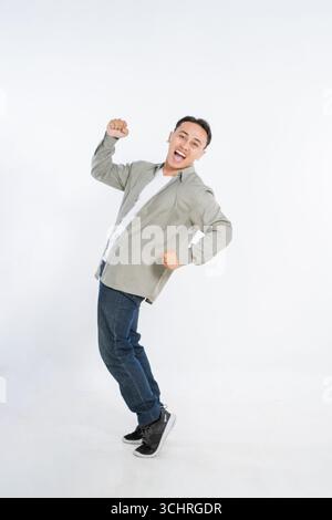 Ein fröhlicher Mann feiert in stilvoller Freizeitkleidung mit energischer Pose Stockfoto