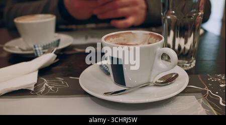Eine Nahaufnahme von zwei leeren Kaffeetassen auf einer Untertasse mit Löffel, serviert an einem gemütlichen Kaffeetisch. Date in der Cafeteria. Stockfoto