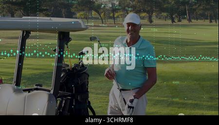 Golfer im Stehen mit Poloshirt, Kappe mit Eisenklub auf dem Fairway des Golfplatzes, mit Golfwagen Stockfoto