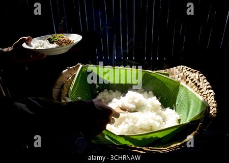 Gekochter weißer Reis, serviert auf grünen Bananenblättern mit einem Holzlöffel. Stockfoto