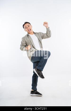 Ein lebendiger und energiegeladener junger Mann, der in einem Studio fröhlich und aufregend tanzt Stockfoto