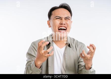 Ein frustrierter junger Mann drückt Wut aus in einem Studio mit einem Plain White Hintergrund Stockfoto