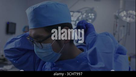 Einstellender Chirurg, OP-Kappe und Handschuhe im Operationssaal, mit Überkopflichtern Stockfoto
