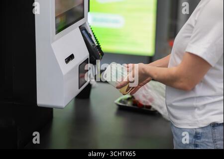 Eine Frau scannt Artikel an einer Selbstkasse. Stockfoto