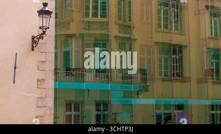 LUXEMBURG, EUROPA - 1. SEPTEMBER 2025 - Glasfassade, die die traditionelle luxemburgische Architektur mit Straßenlaterne und Schild des Stadtmuseums widerspiegelt Stockfoto