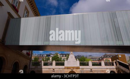 LUXEMBURG, EUROPA - 1. SEPTEMBER 2025 - moderner Glassteg über historischen Gebäuden und Brücke im Stadtzentrum von Luxemburg Stockfoto