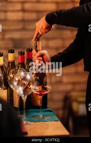 Sommelier öffnet eine Flasche Wein bei einer eleganten Verkostung mit Gläsern auf dem Tisch Stockfoto