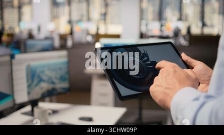 Nahaufnahme eines Forschers, der Turbinenkomponenten auf einem Tablet analysiert, um die Nachhaltigkeit zu maximieren. Der CAD-Designer verwendet App auf dem Gerät, um die Aerodynamik der Rotorblätter zu optimieren und die saubere Energieabgabe zu verbessern, Kamera A Stockfoto